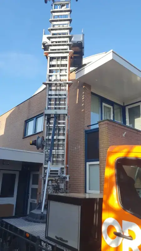 Detail van een uitgeschoven ladderlift tegen een gebouw
